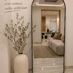 Un salon lumineux avec un grand miroir au mur, reflétant la lumière naturelle